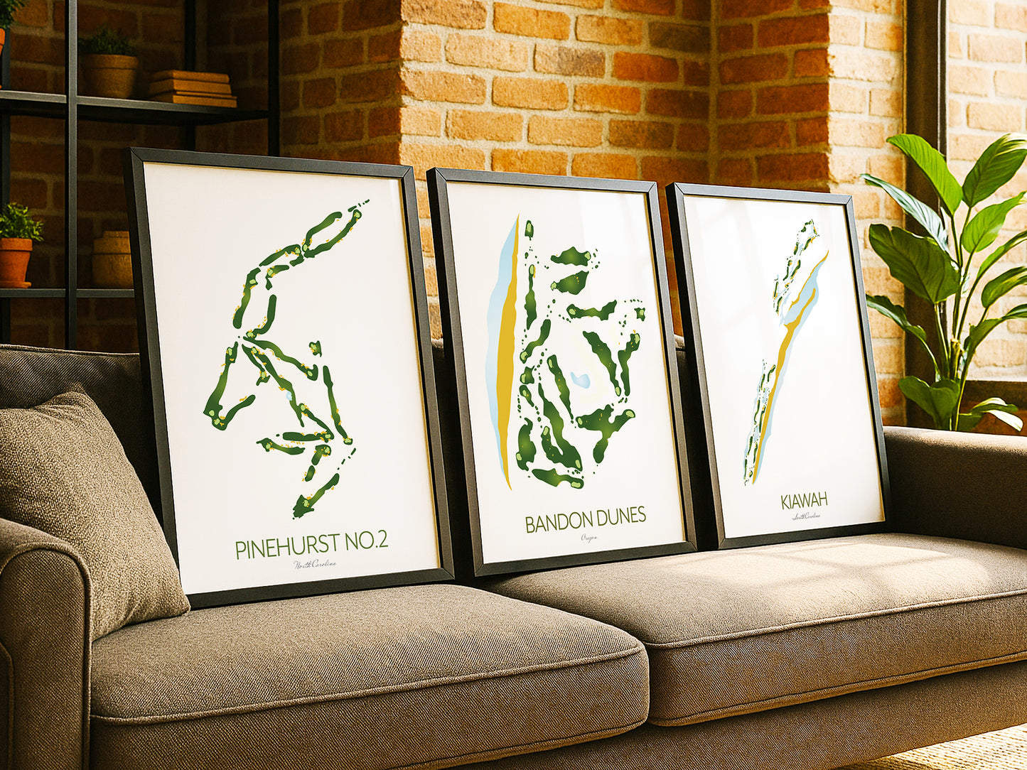 Three framed golf course maps on a couch with a brick wall background
