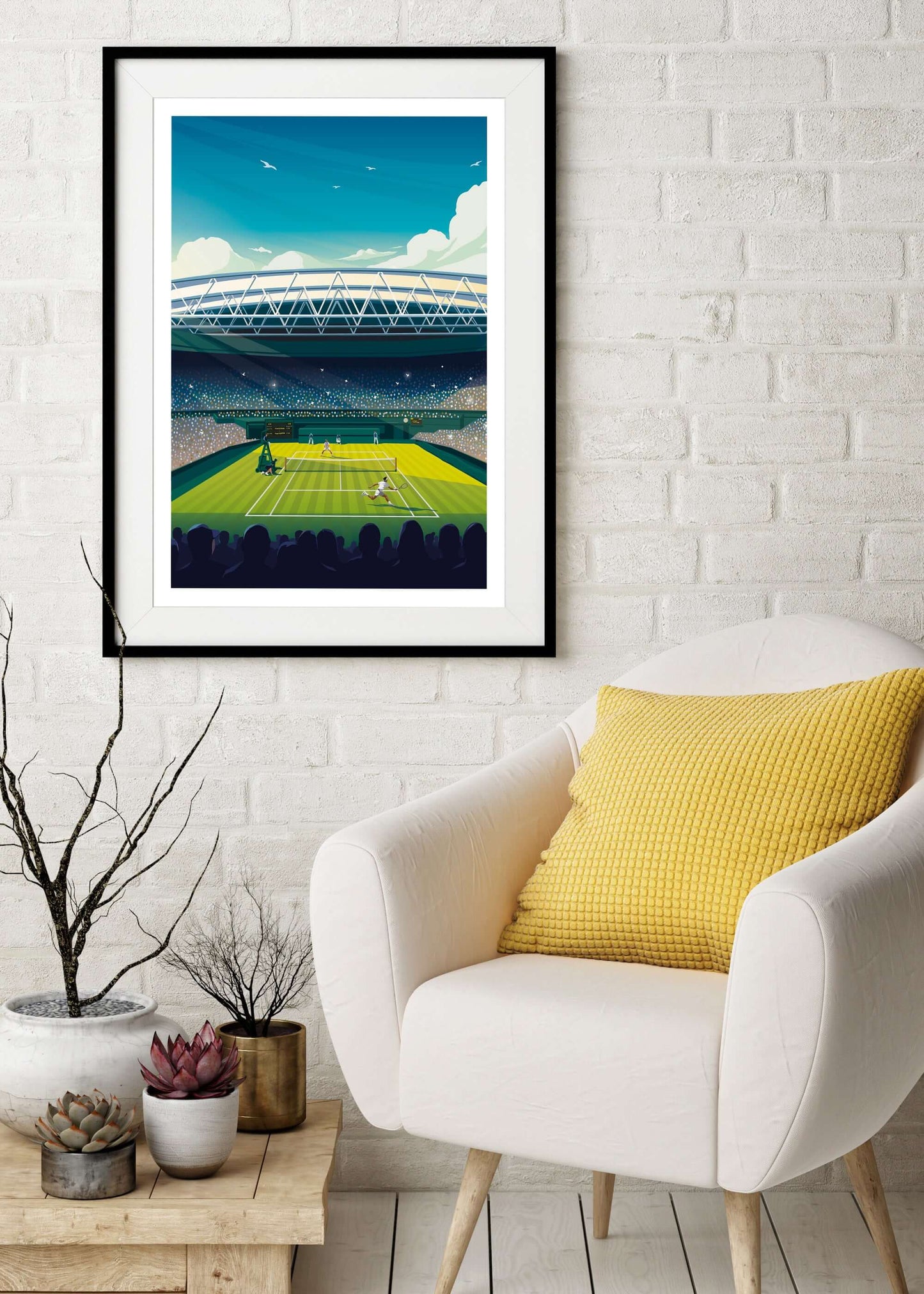 Framed Wimbledon artwork of centre court, hung on a wall above a cream armchair with a yellow cushion.
