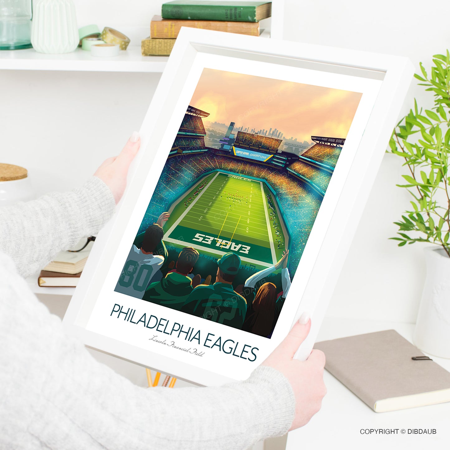 Framed artwork of a football stadium with 'Philadelphia Eagles' text, held by a person.