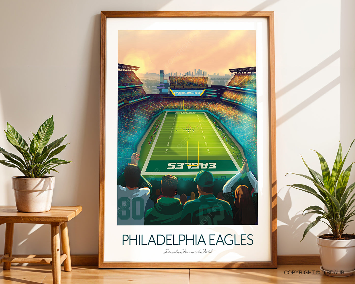 Framed poster of a football stadium with 'Philadelphia Eagles' text, placed on a wooden floor with plants around.