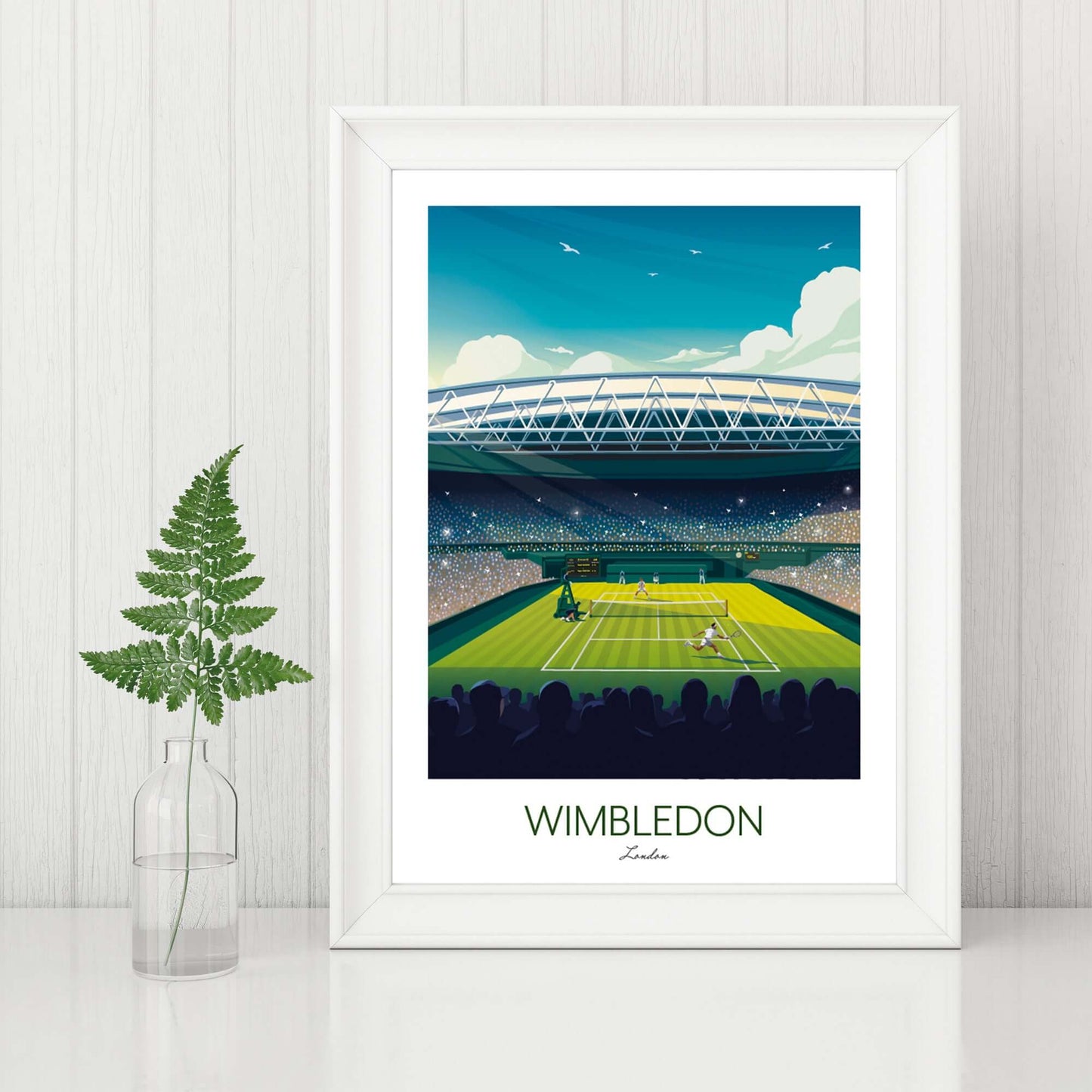 Tennis art print of Wimbledon in a white frame, displayed on a sideboard beside a fern plant.