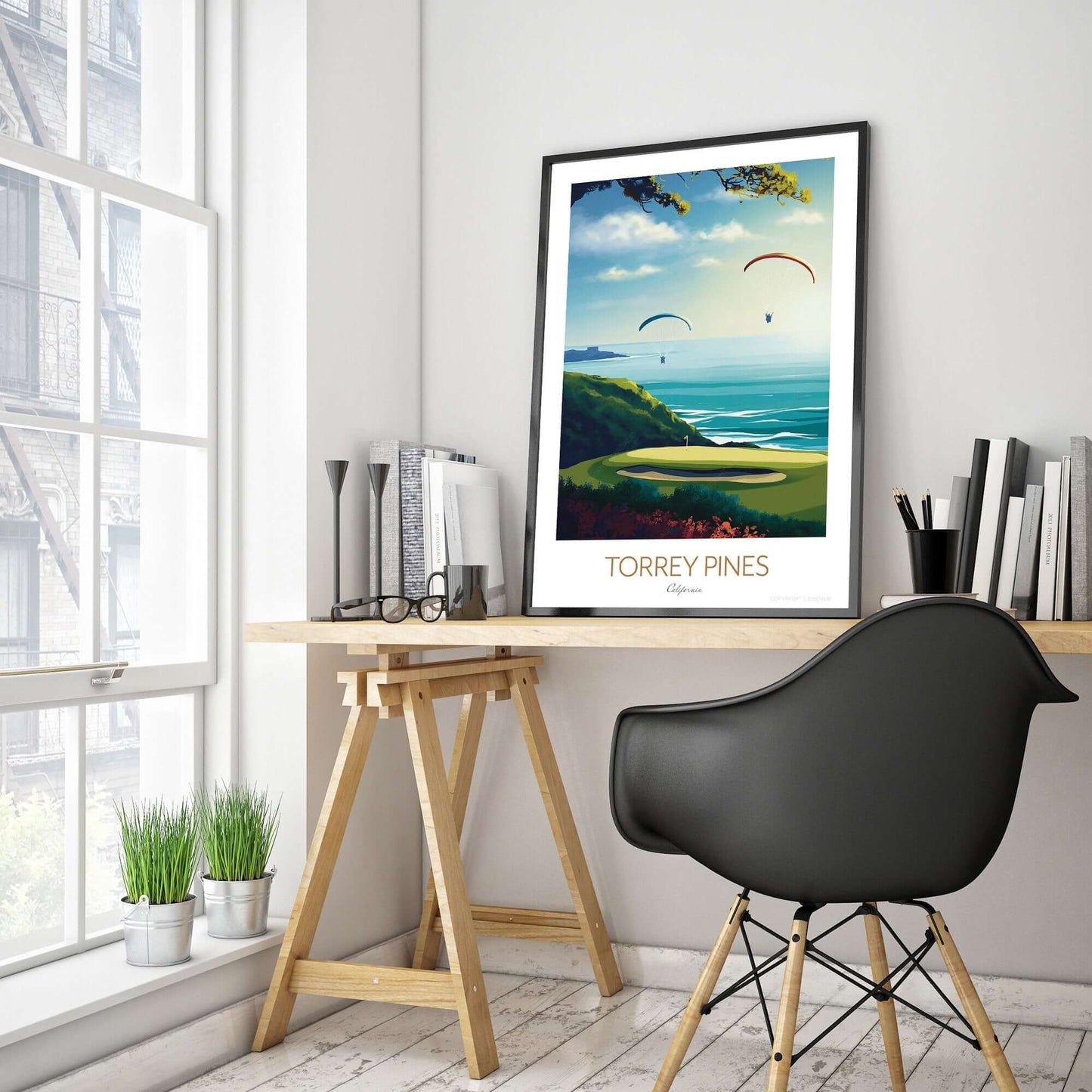 A golf course print of Torrey Pines, with a black frame placed on a office desk.