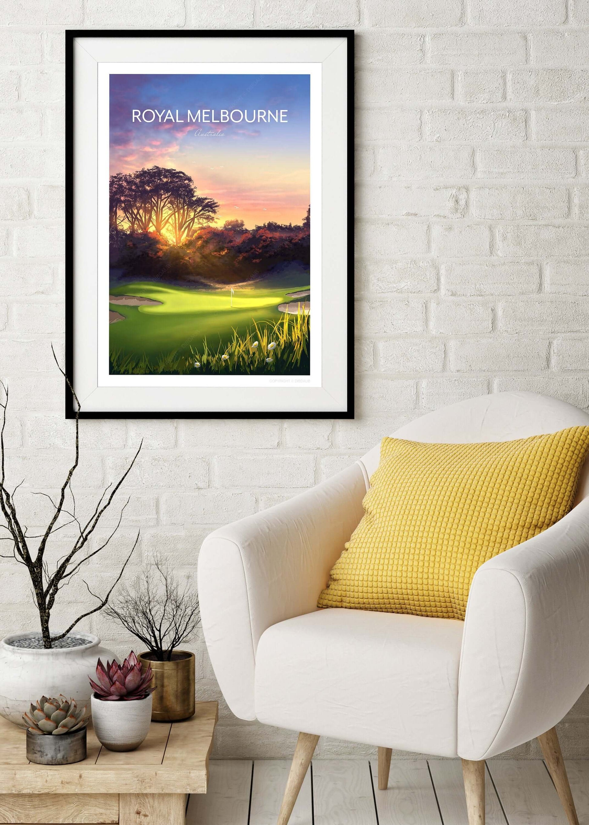 Royal Melbourne golf poster of the West Course 5th hole, in a black frame hanging on the wall above an armchair.