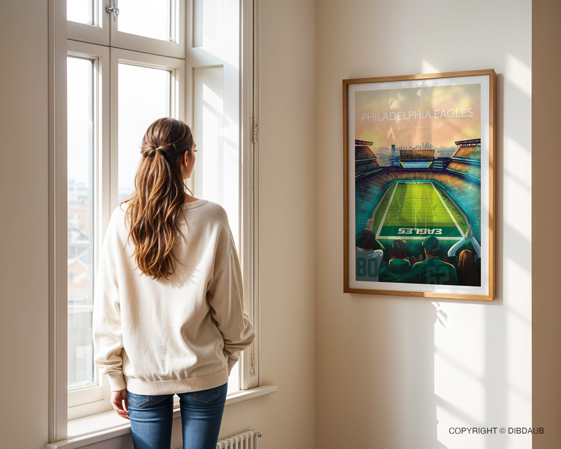 Woman standing by a window looking at a framed artwork of a Philadelphia Eagles Lincoln Financial Field stadium.