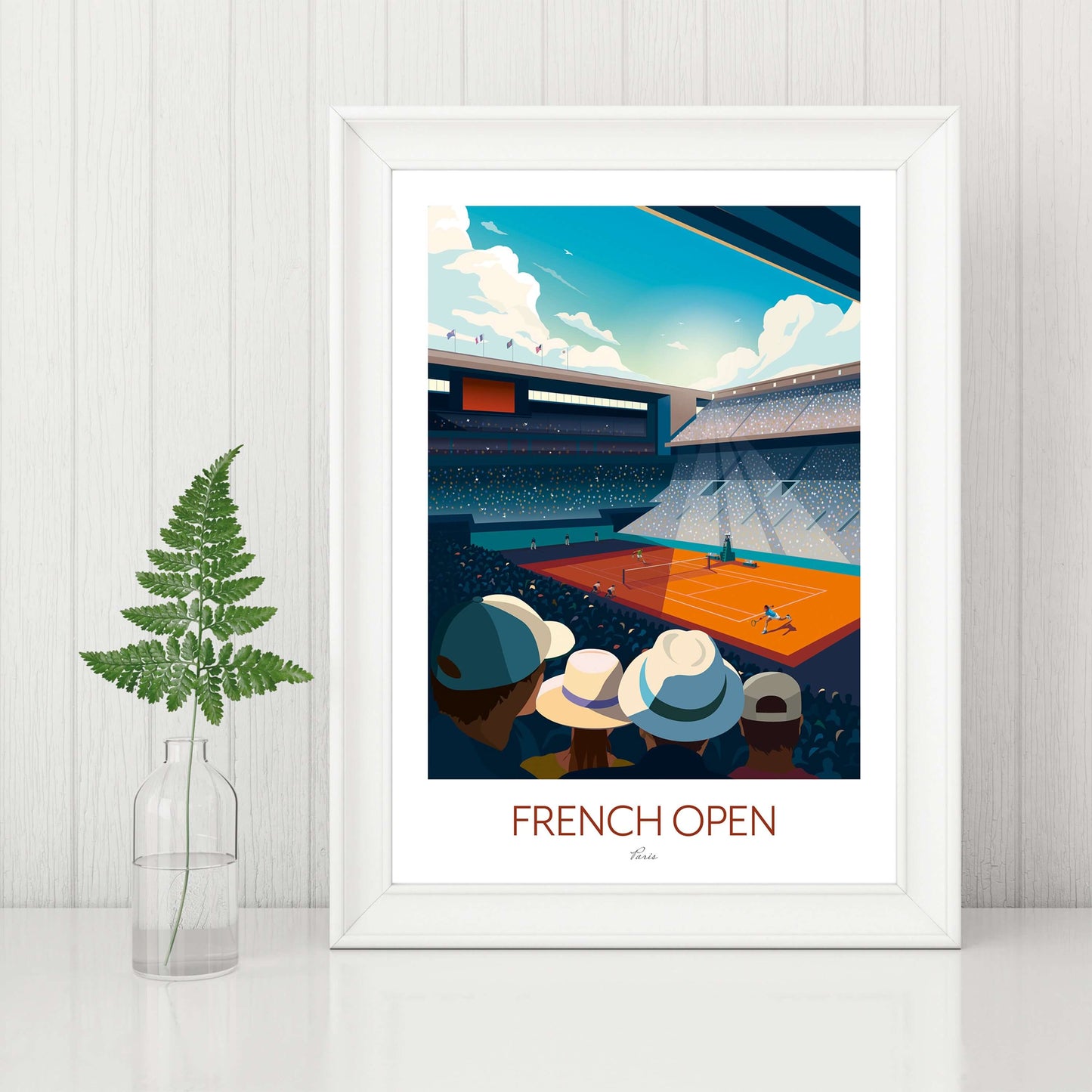 Roland Garros tennis art print in a white frame, displayed on a sideboard beside a plant.