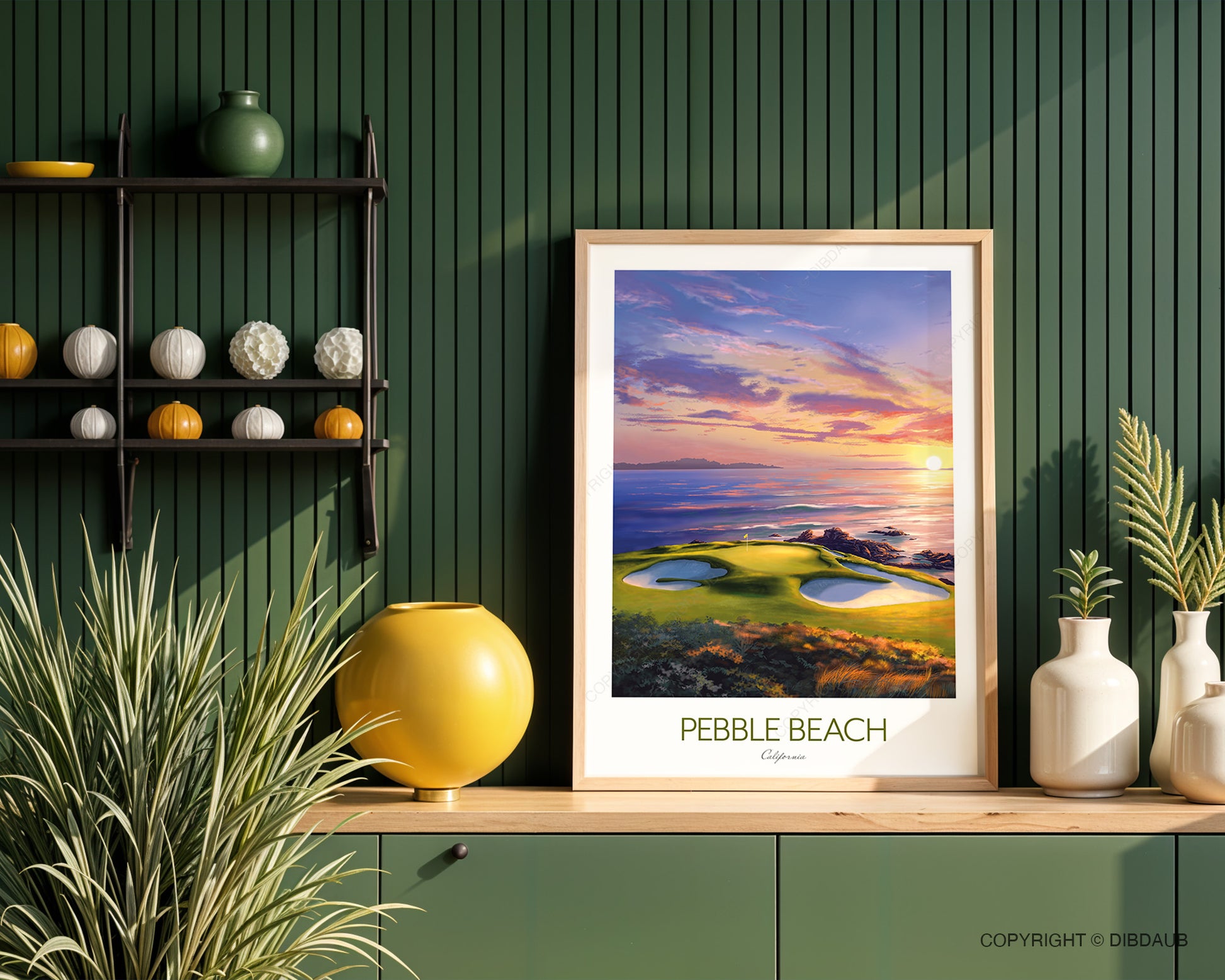 Framed artwork of Pebble Beach on a wooden shelf against a green wall with decorative items. Pebble Beach golf wall art capturing the dramatic 7th hole beside the Pacific coastline.