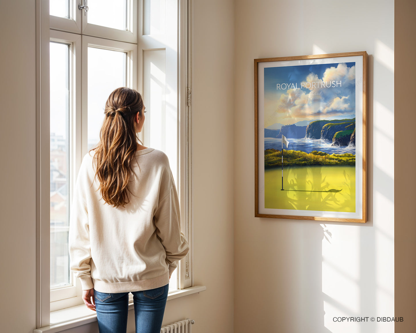 Woman standing by a window looking at a framed golf course art print of Royal Portrush.