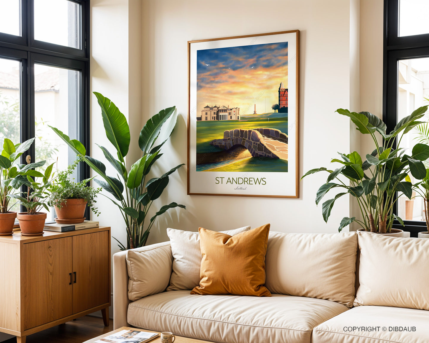 St Andrews golf course artwork with vibrant colours and the iconic Swilcan Bridge in the foreground. Framed golf print of St Andrews is in a living room with above a beige sofa with decorative pillows and plants either side.