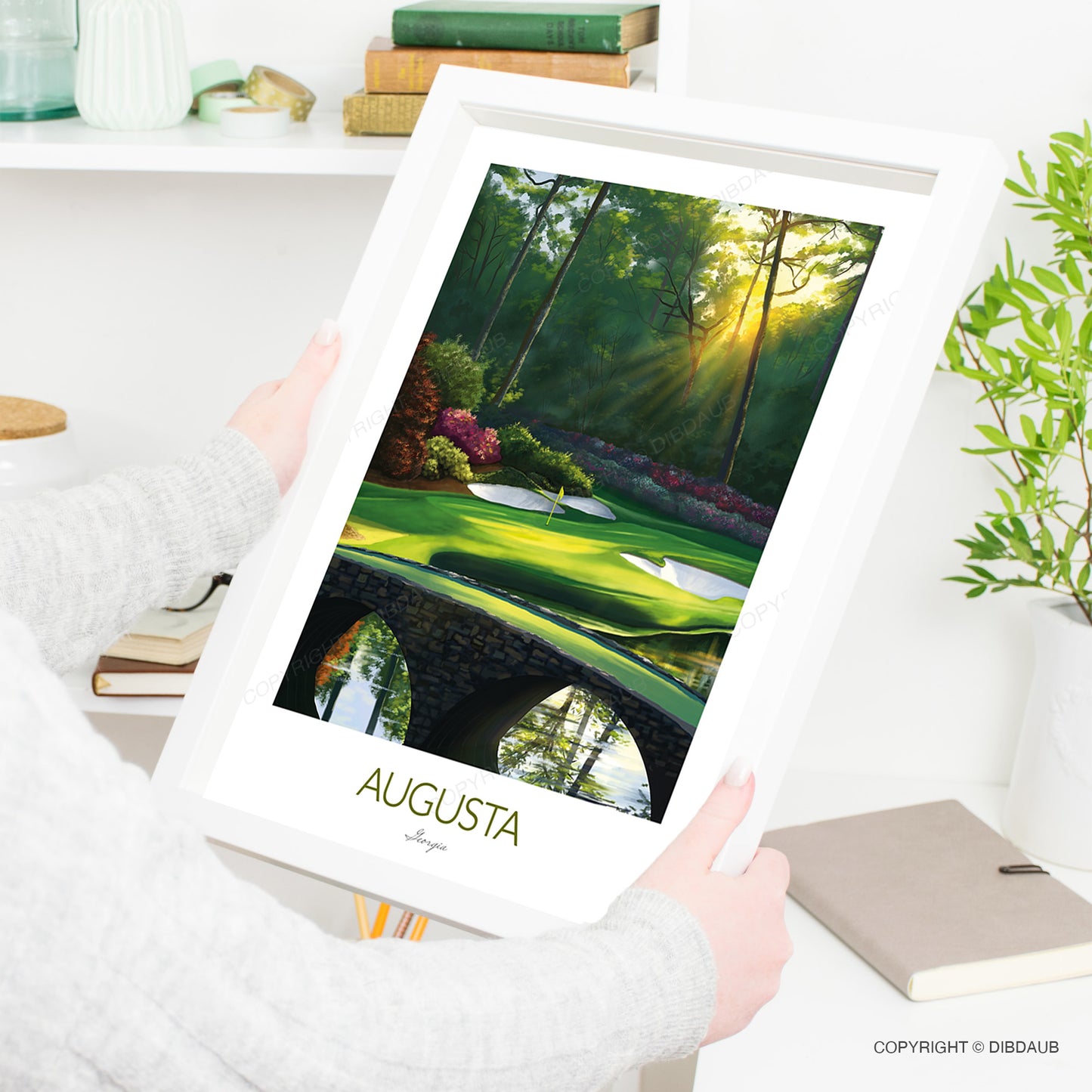 Person holding a framed art print of Augusta National golf course.