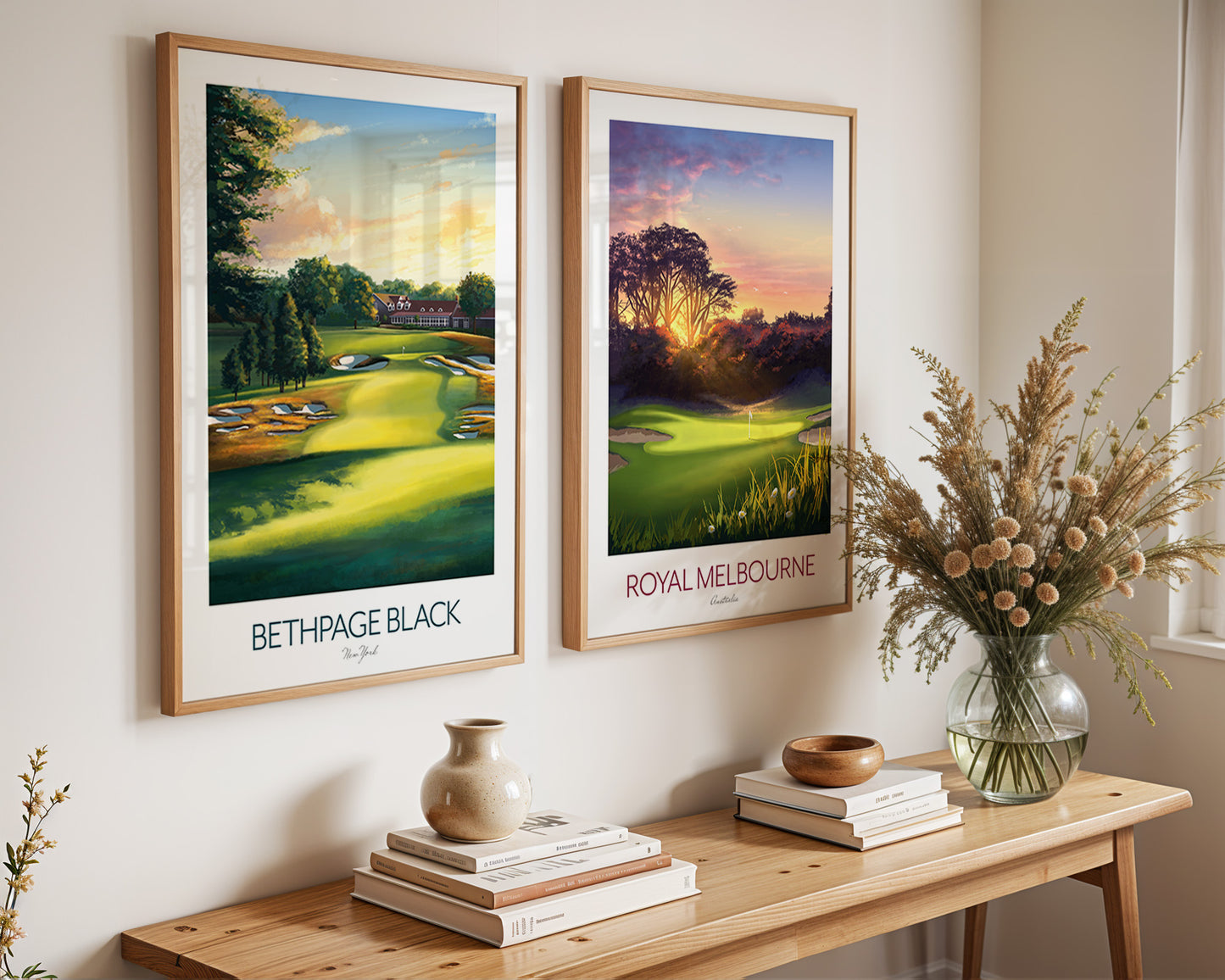 Two framed golf course prints of Bethpage and Royal Melbourne on a wall above a wooden console table with decorative items.