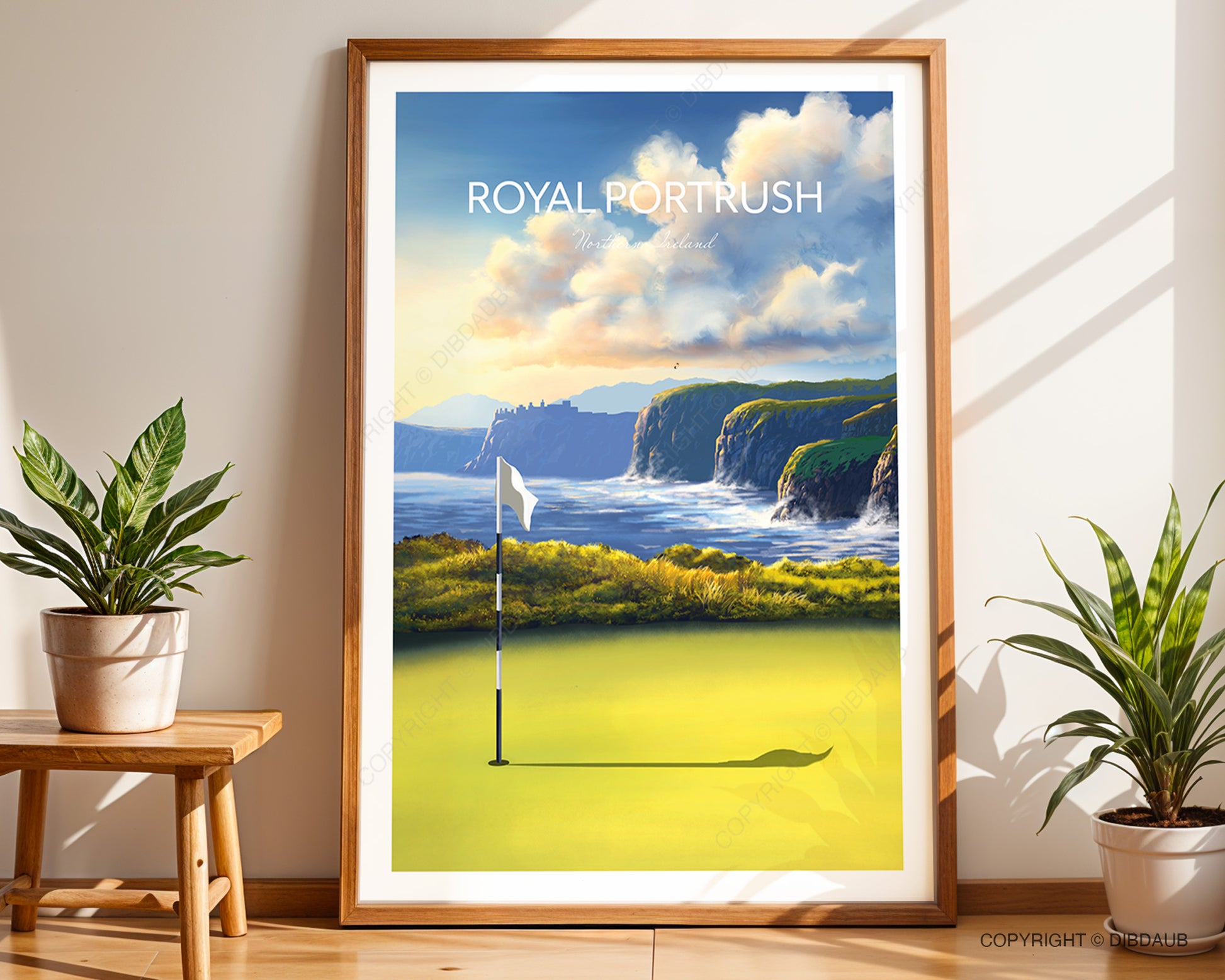 Framed golf course art print of The Open at Royal Portrush, leaning against a wall with plants either side.