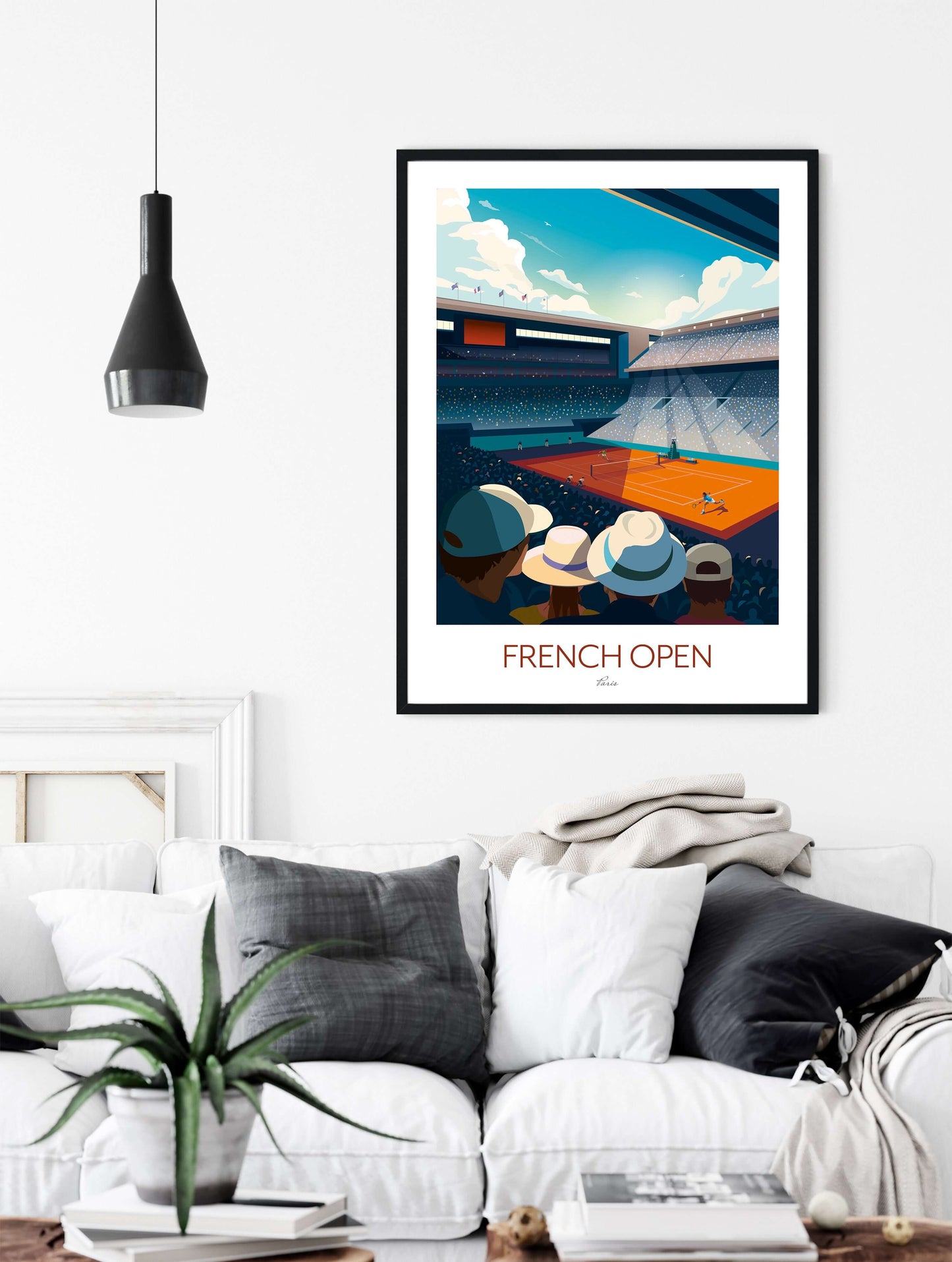 Framed art print of Philippe-Chatrier tennis court at Roland Garros, hanging on a living room wall above a white sofa. The French Open tennis print depicts Rafael Nadal playing with the crowd watching in anticipation.