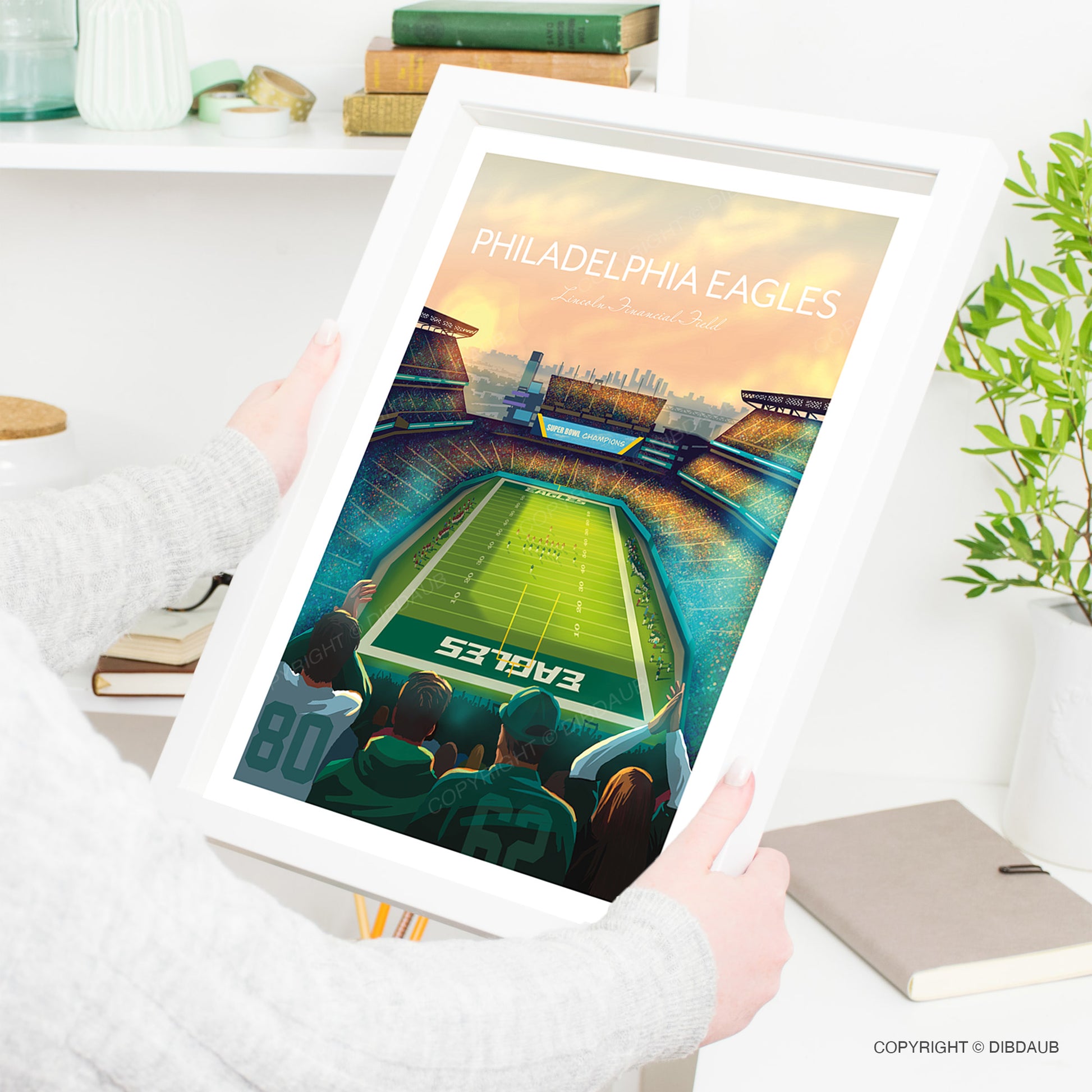 Framed poster of Philadelphia Eagles football stadium being held by a lady.