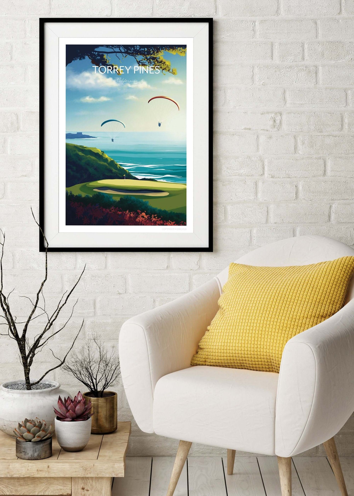 Torrey Pines golf course print, in a black frame hanging on the wall above an armchair.