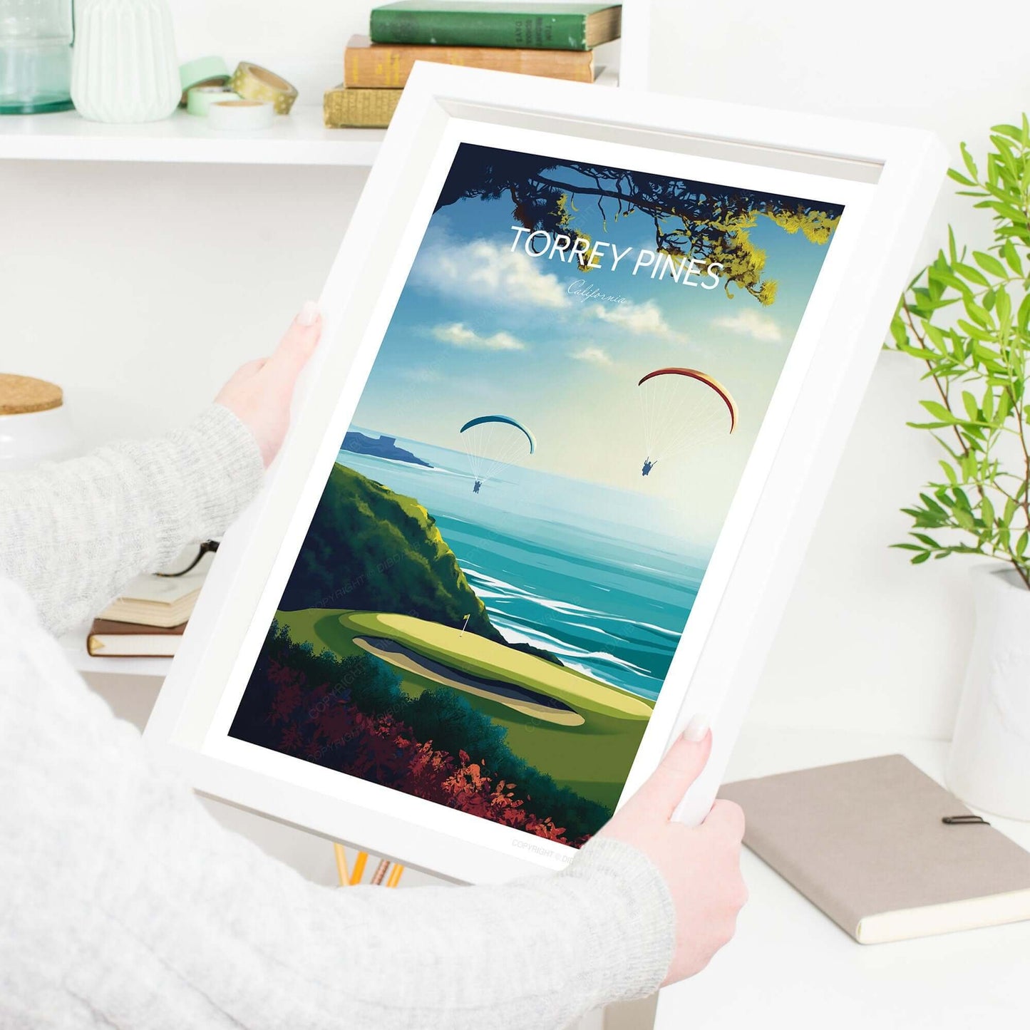 Lady holding a golf course print of Torrey Pines with a white frame.