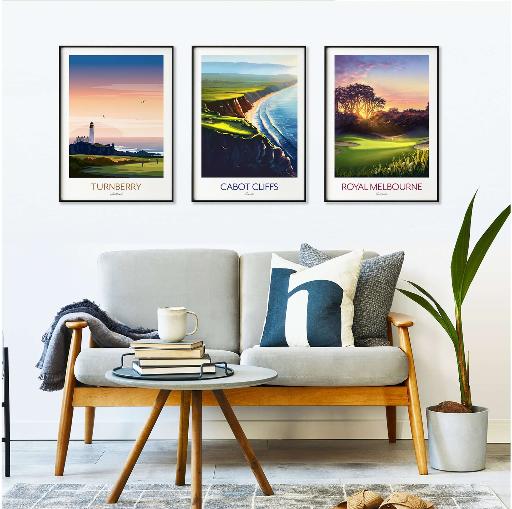 A set of three framed golf course posters of Royal Melbourne, Cabot Cliff and Turnberry, hanging on a wall above a sofa.