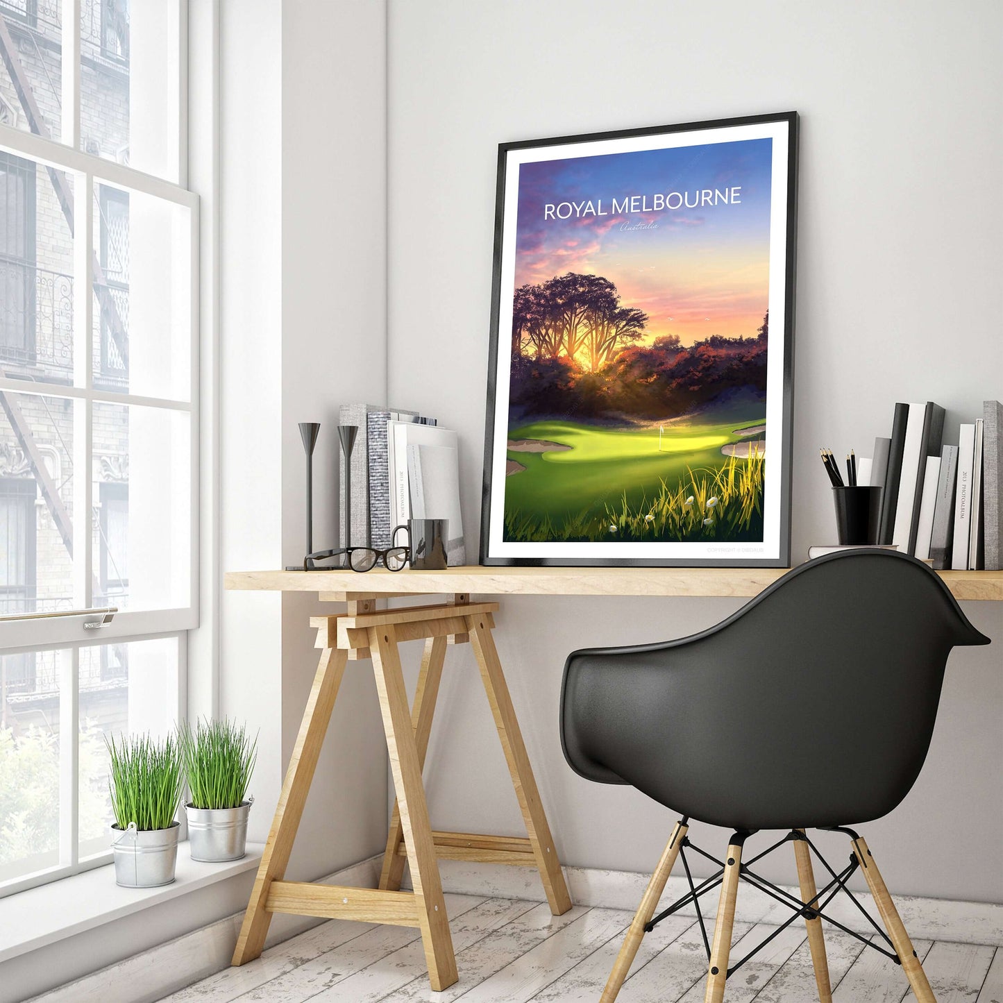 A framed golf poster of Royal Melbourne West Course 5th hole, sitting on a home office desk.