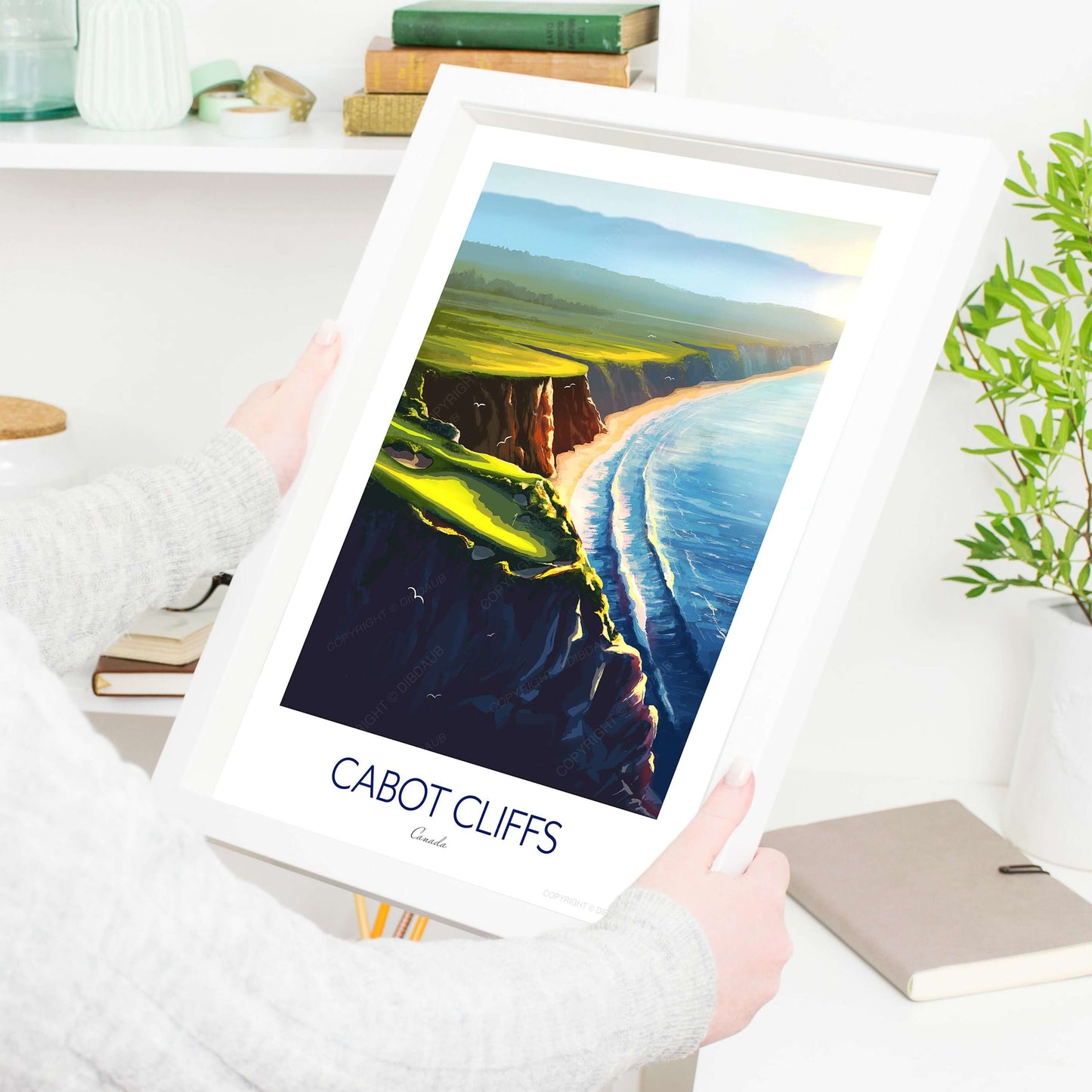 A lady holding a white frame containing an art print of Cabot Cliffs golf course, Canada.