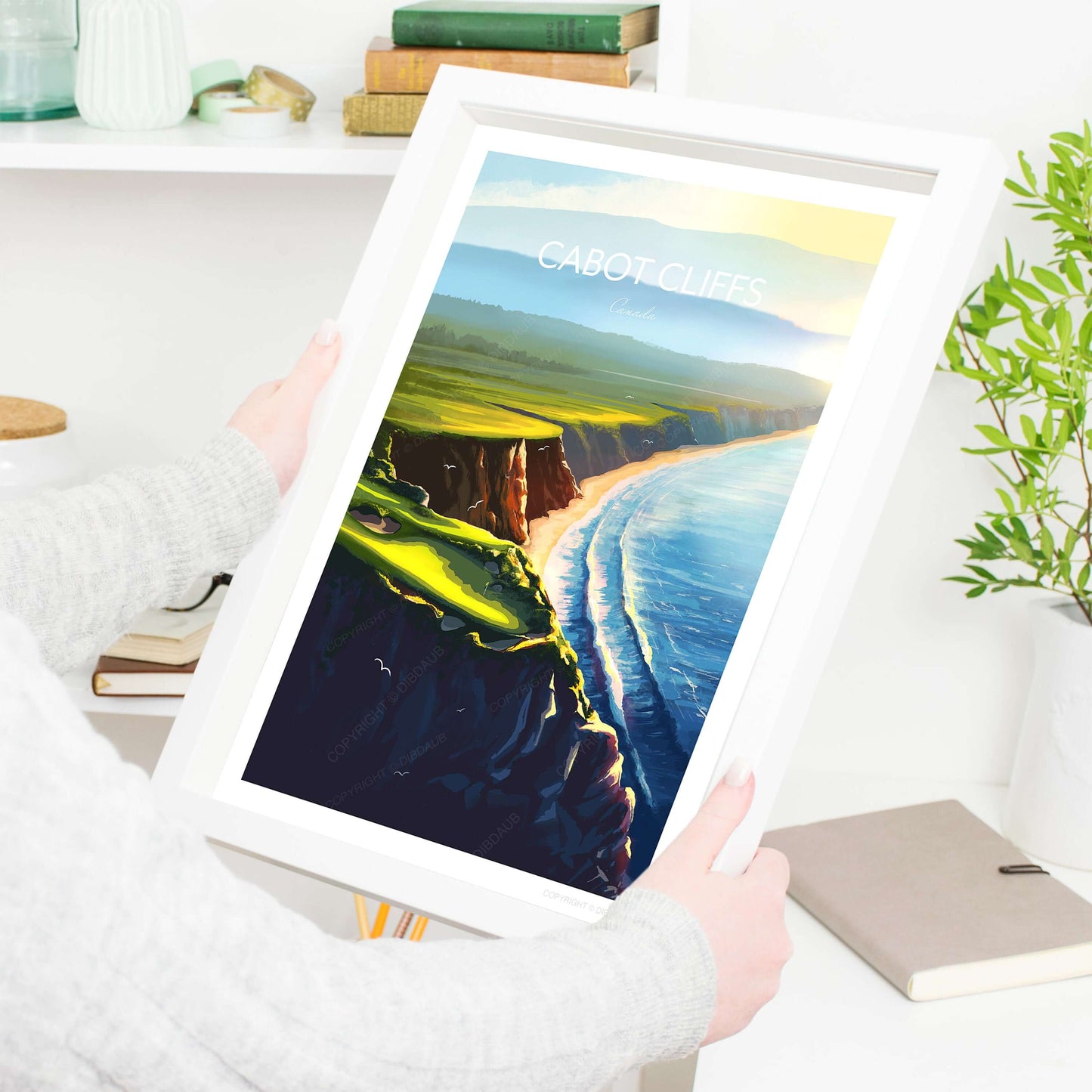 A lady holding a white frame with a golf course print of Cabot Cliffs 16th Hole, Canada.