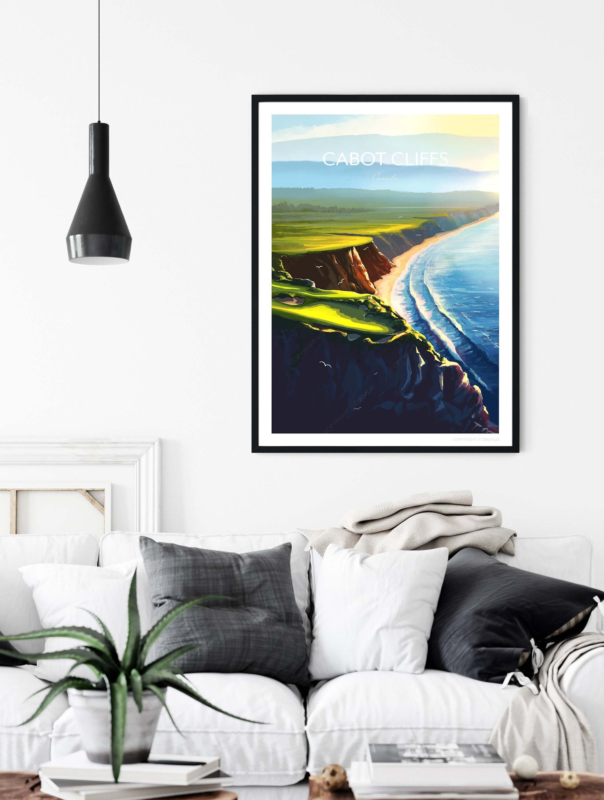 Framed print of Cabot Cliffs 16th hole, hanging on a living room wall above a sofa with cushions.